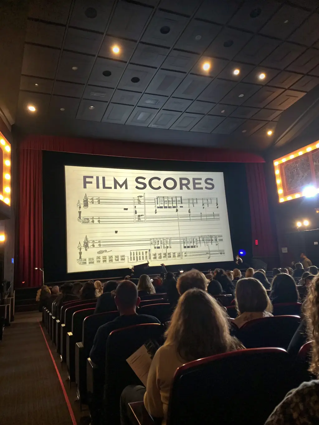 A vibrant image capturing a scene from one of the adventure film screenings at the festival, showcasing an engaged audience watching a film about mountain climbing.